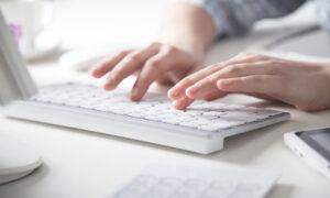 Hände, die auf einer Computertastatur tippen.