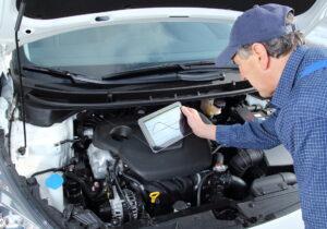 Automechaniker mit Tablet führt Fahrzeug-Analyse durch
