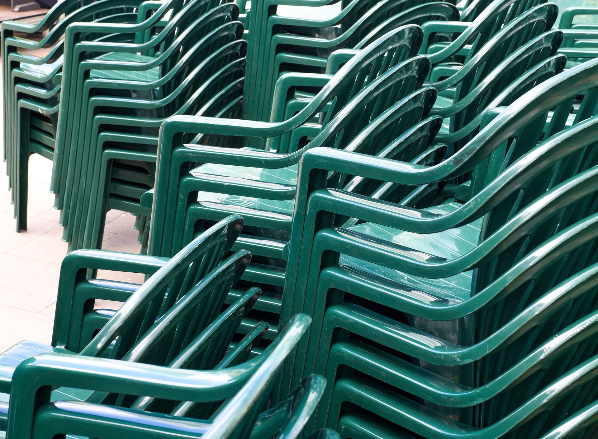 Gestapelte grüne Kunststoffstühle für Eventbestuhlung im Freien | Stehtischhussen